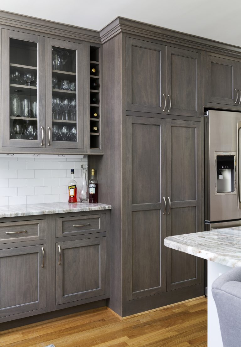gray contrast cabinetry with glass door uppers and subway tile backsplash