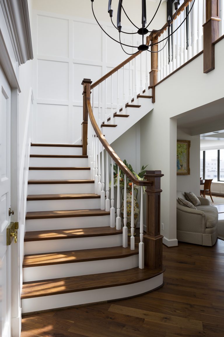stairway with dark wood floors white wainscot walls eclectic chandelier
