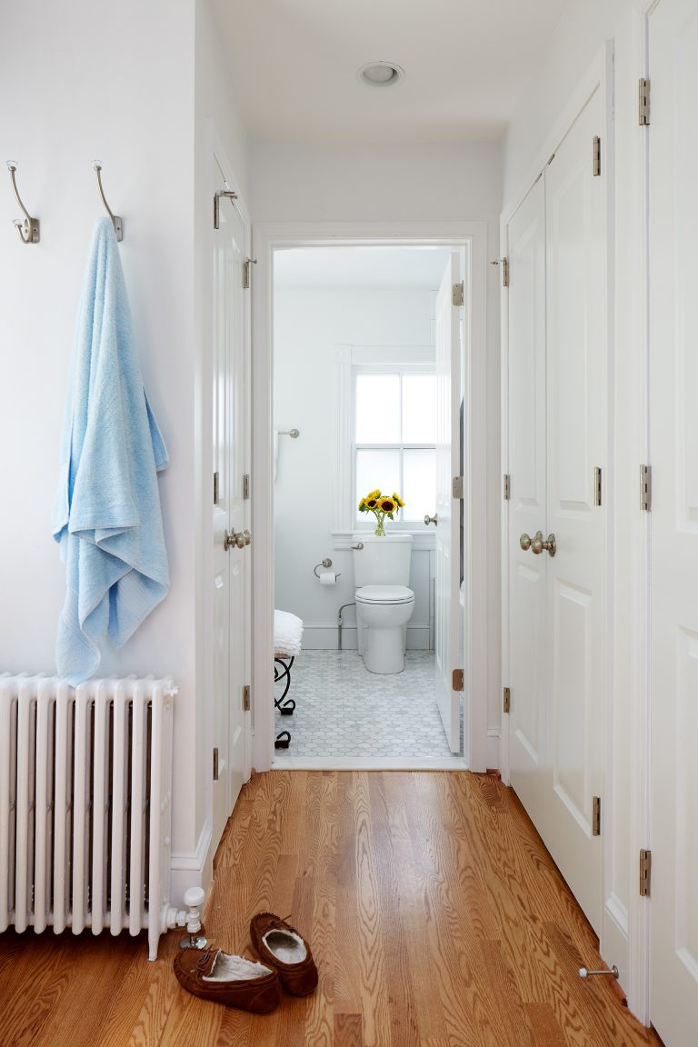 hallway leading to renovated bright white bathroom