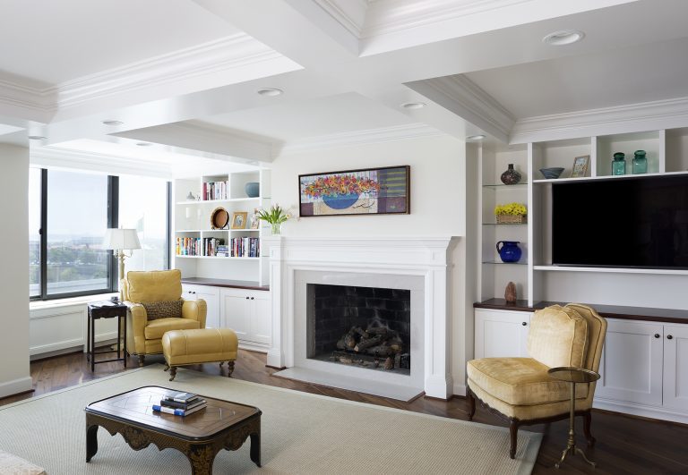 living area with large windows built in storage and shelving coffered ceiling and fireplace