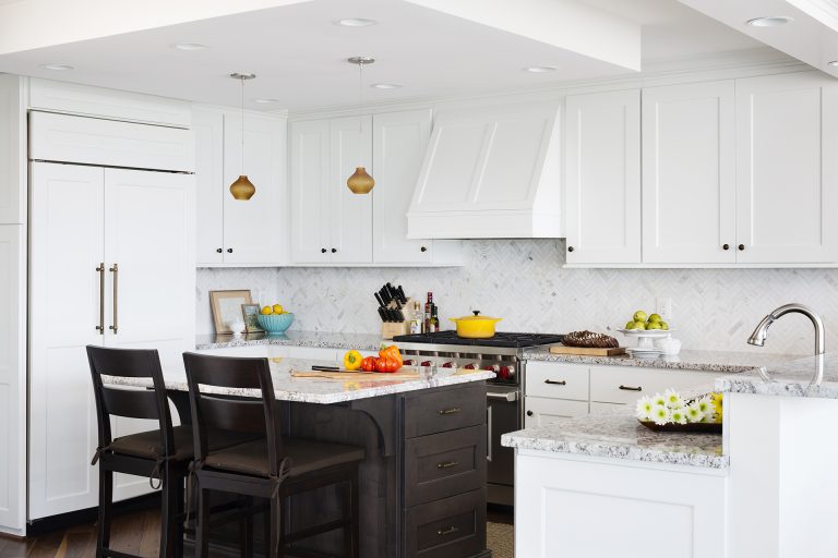 white outer cabinetry dark island cabinetry seating at island and pendant lighting paneled refrigerator