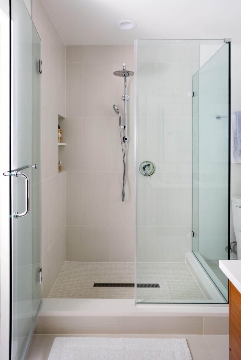 shower with glass wall and white tile storage nook in wall