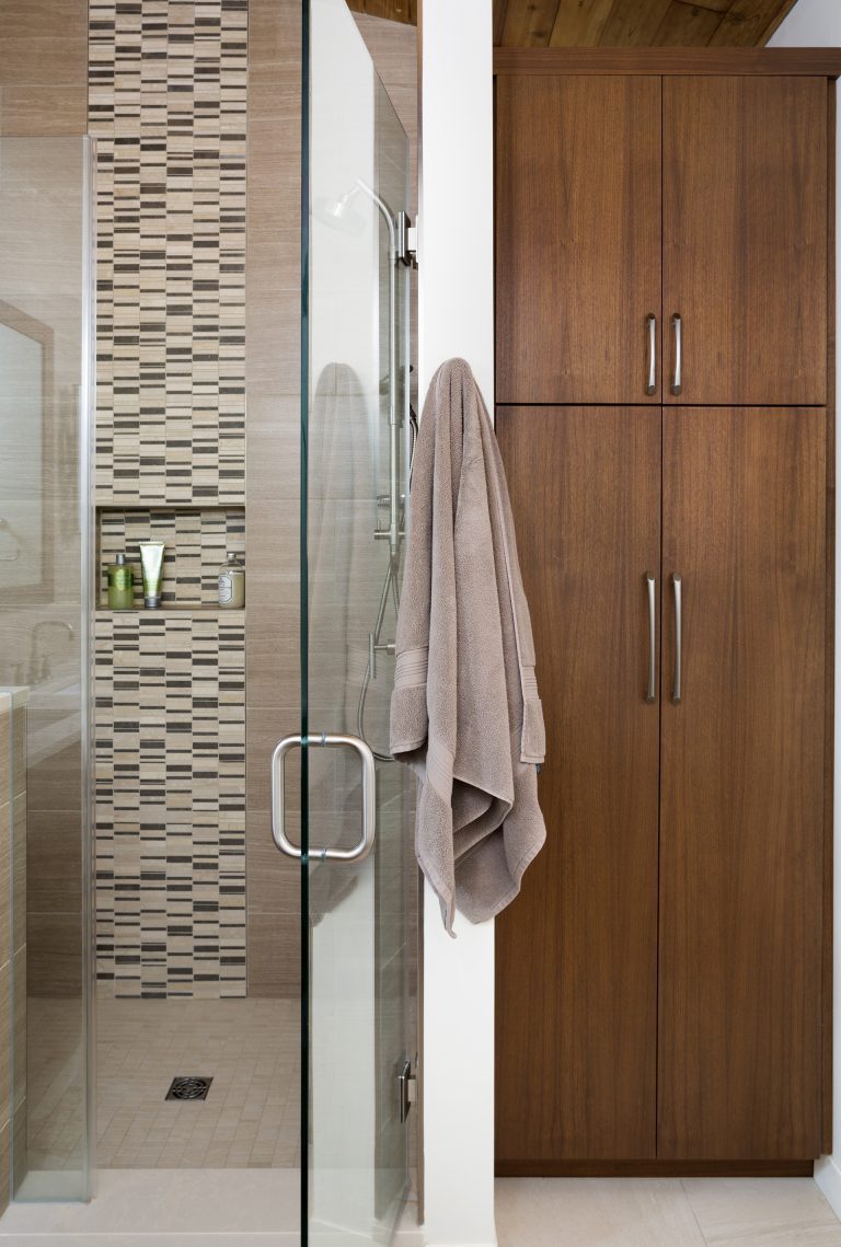 separate shower stall with glass door storage nook and tile detail floor to ceiling storage dark wood cabinetry