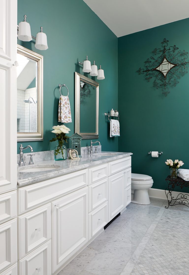 bathroom with teal walls vanity with white cabinetry and double sinks plenty of storage sconce lighting floor tile detail