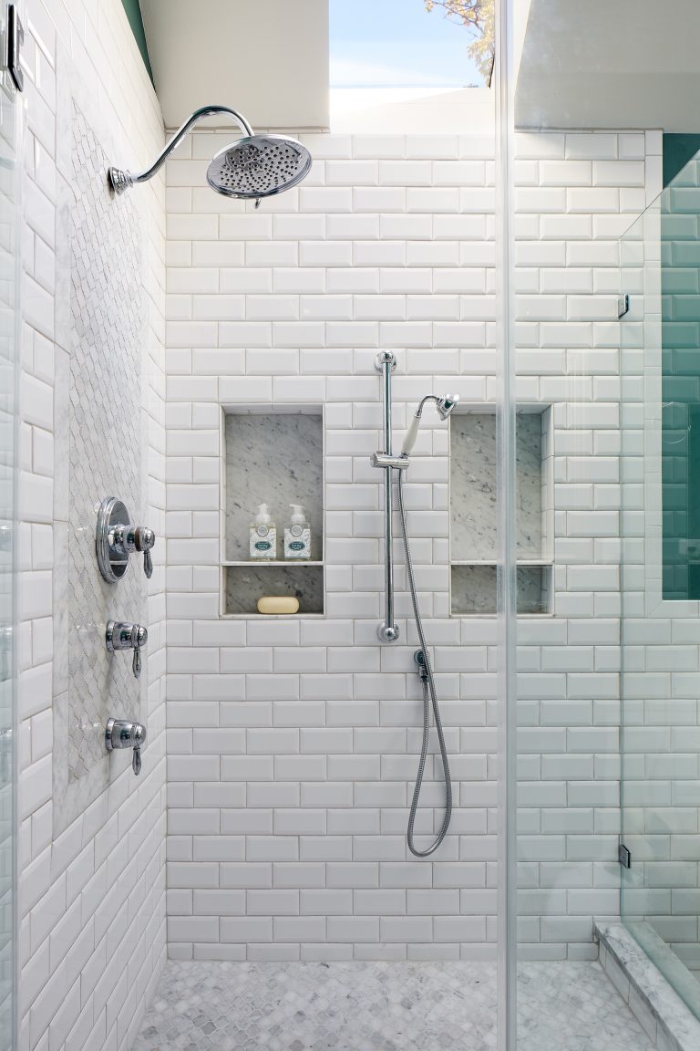 shower stall with white subway tile and glass door storage nooks in wall skylight