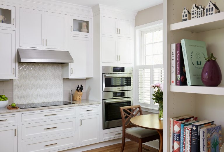 electric stovetop and stainless steel hood and wall oven with backsplash tile detail