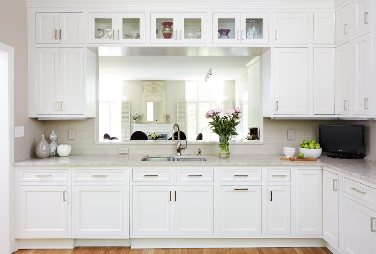 kitchen with wood floors and white cabinetry passthrough into dining area