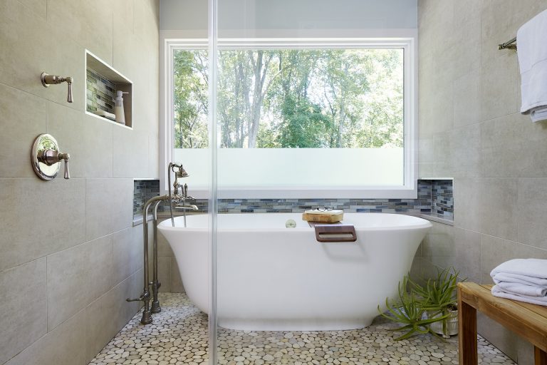 shower area with glass wall and freestanding tub green and neutral color palette relaxing