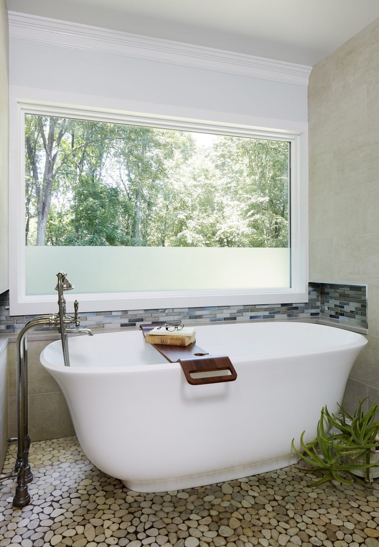 freestanding bathtub under window with partially frosted glass pebble tile outdoor vibe