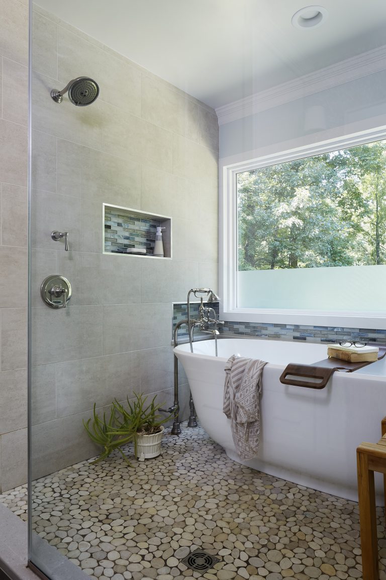 shower area with big window and glass wall freestanding tub storage nooks with accent tile pebble tile floor