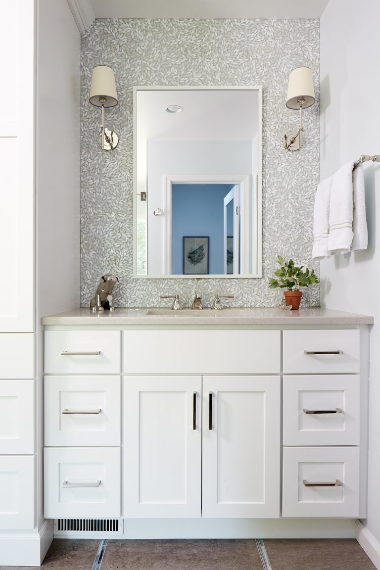 bathroom vanity white cabinetry tile feature wall behind mirror and sconce lighting