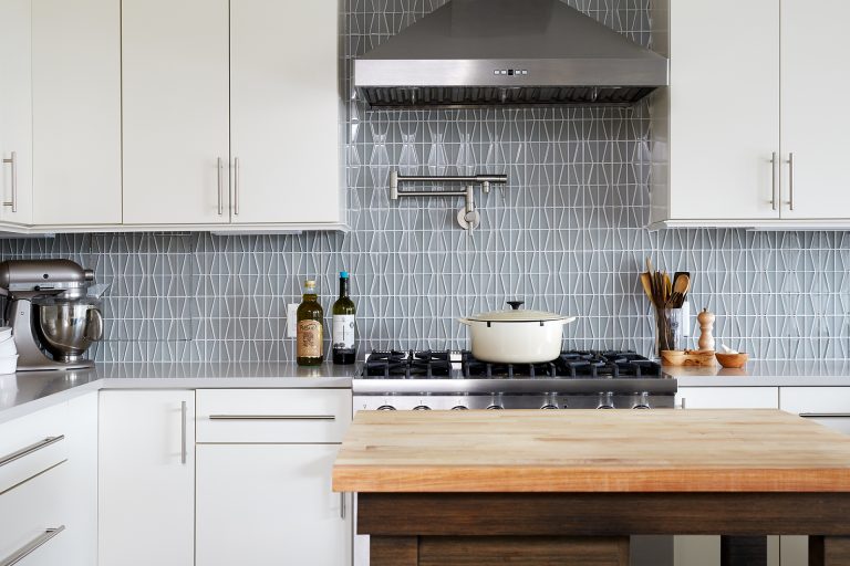 white outer kitchen cabinetry and natural wood island stainless steel gas range and hood with pot filler