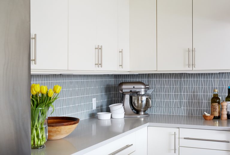 renovated kitchen with white cabinetry and soft blue geometric backsplash gray countertops