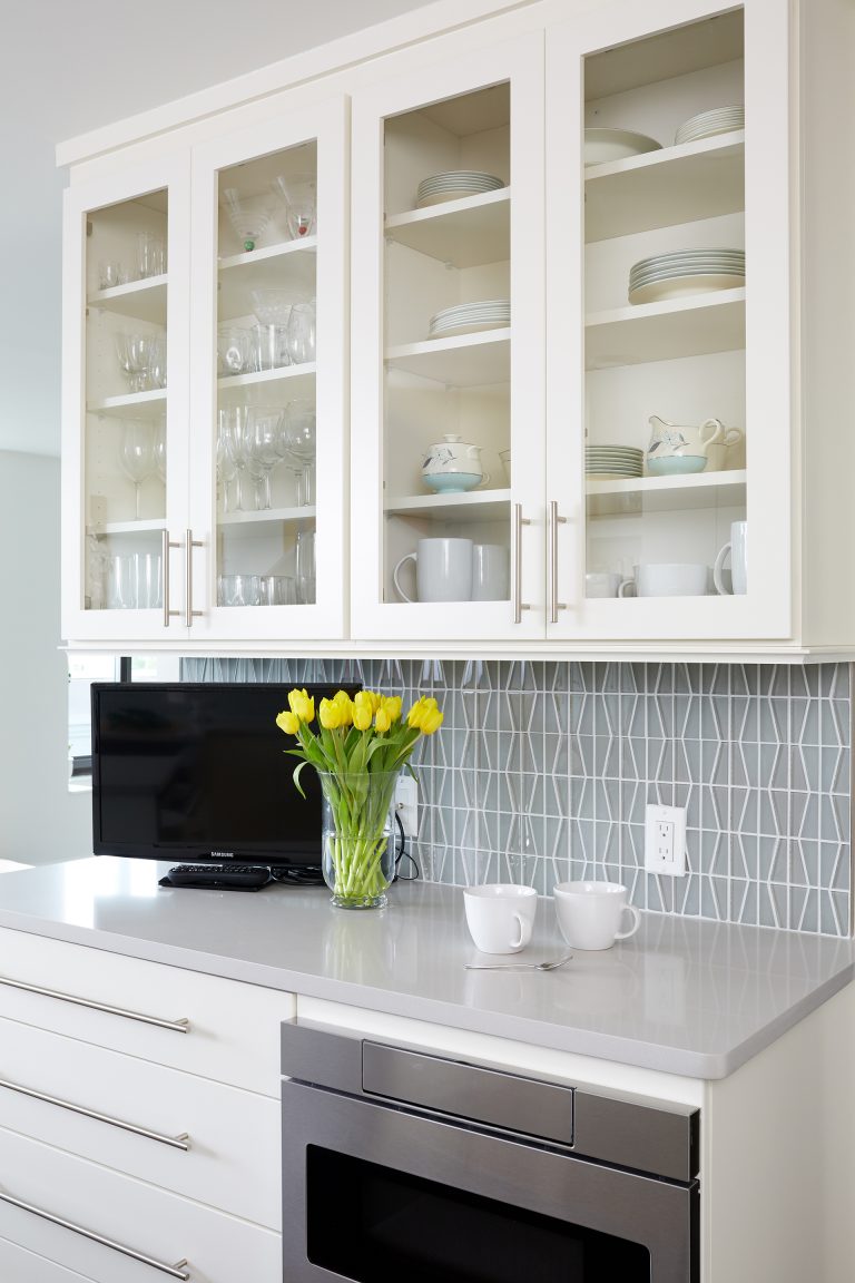 kitchen with white cabinetry and glass door uppers soft blue geometric tiling