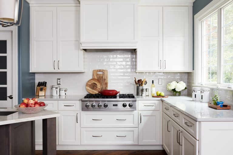 kitchen with wood floors white cabinetry stainless steel gas stovetop subway tile backsplash