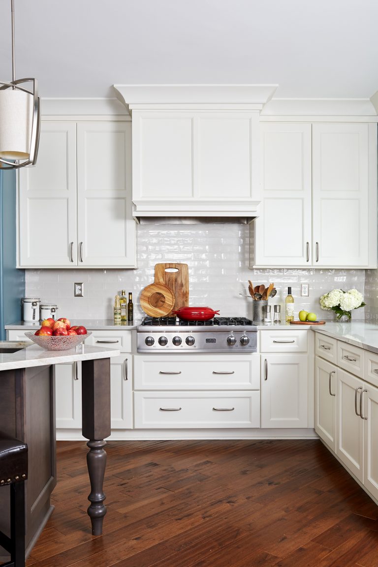 kitchen with wood floors white cabinetry stainless steel gas stovetop subway tile backsplash