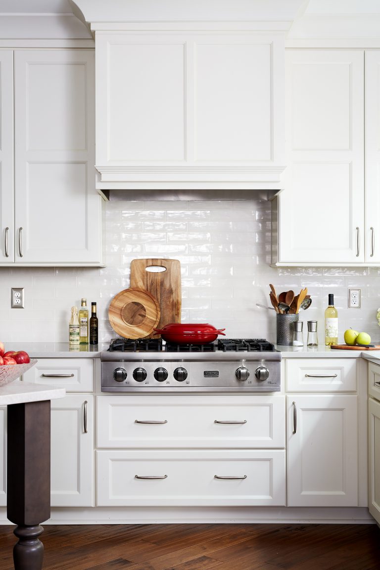 kitchen with wood floors white cabinetry stainless steel gas stovetop subway tile backsplash