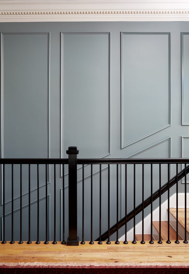 interior staircase with dark wood banister gray paneled walls