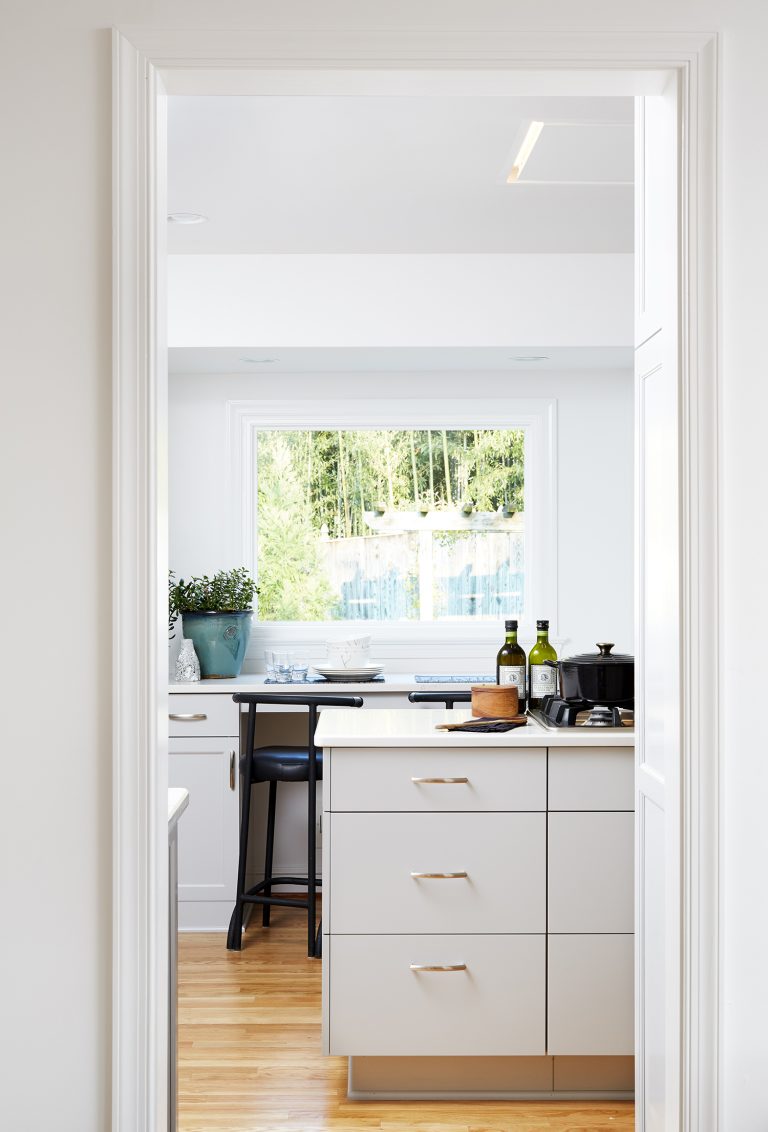 view into kitchen white cabinetry wood floors large window