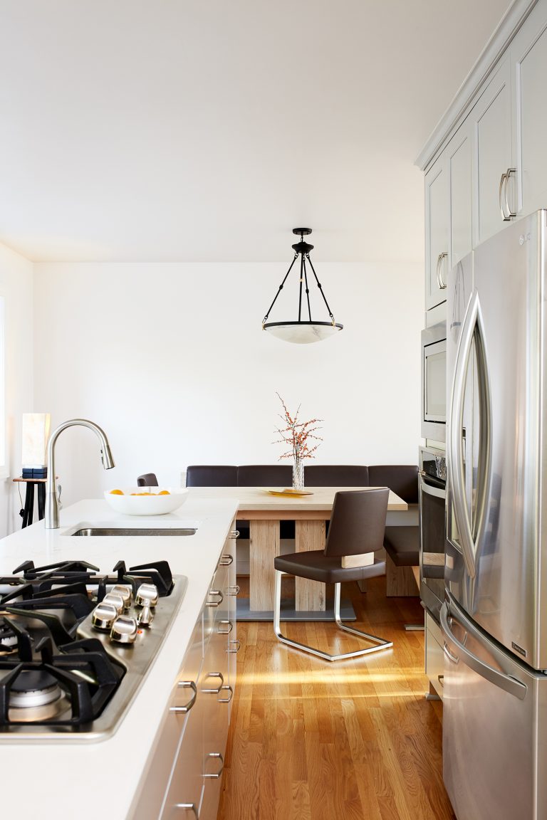 kitchen open to dining area white cabinetry stainless steel appliances and gas stovetop wood floors