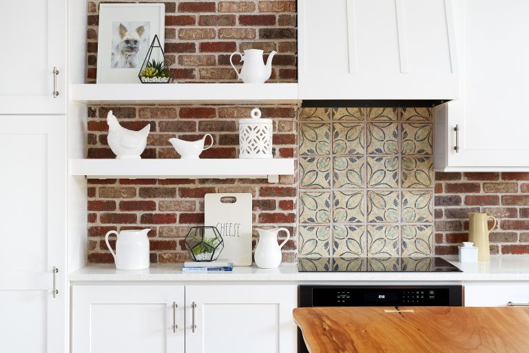 exposed brick wall behind white cabinetry open shelving tile backsplash detail behind electric range