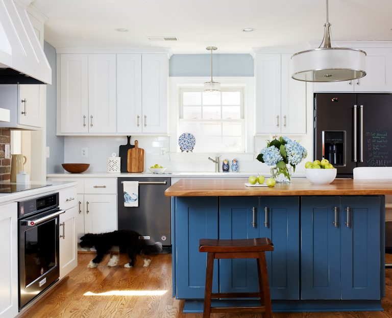 tall white cabinets with pull handles, stainless steel appliances, wood floors, small window above the farmhouse sink