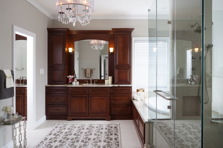 bathroom vanity dark wood cabinetry lots of storage separate paneled bathtub and shower with glass wall chandelier