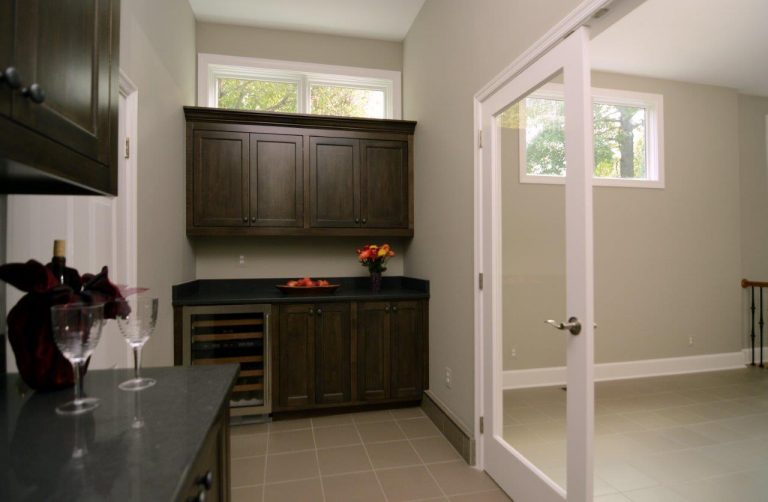 bar area with mini fridge glass doors and small window above cabinets