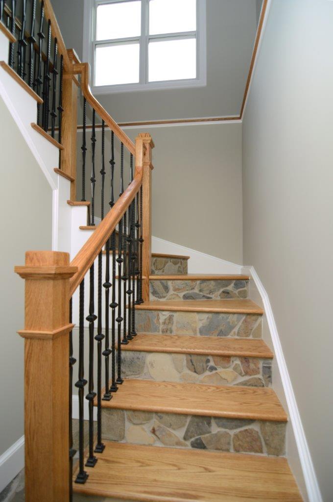 staircase with light wood banister and treads stone risers