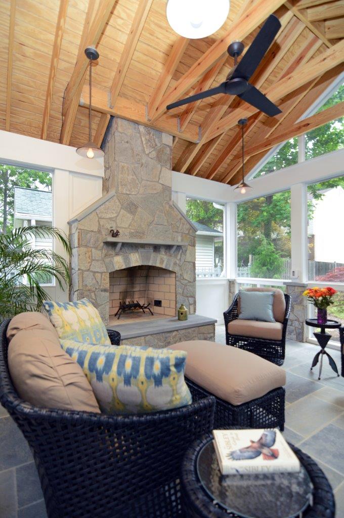 screened in porch addition with stone fireplace and wood ceiling with beams flagstone floors