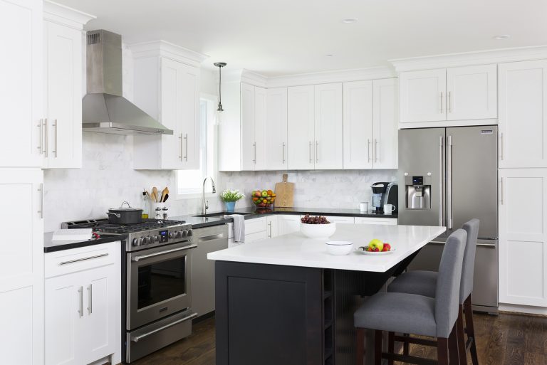 kitchen with white cabinetry and stainless steel appliances navy blue island cabinetry seating at island