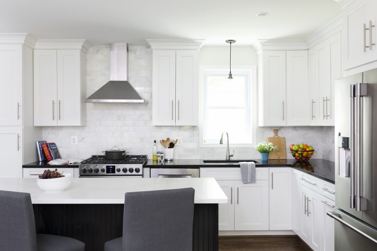 renovated kitchen with white cabinetry stainless steel appliances sink in front of window with pendant lighting above