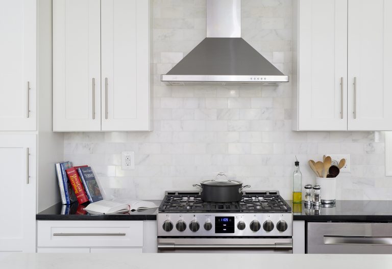 stainless steel gas range and hood subway tile backsplash