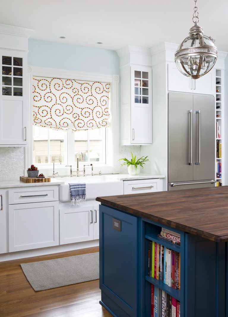 white kitchen with island blue cabinetry and open shelving on side pendant lighting