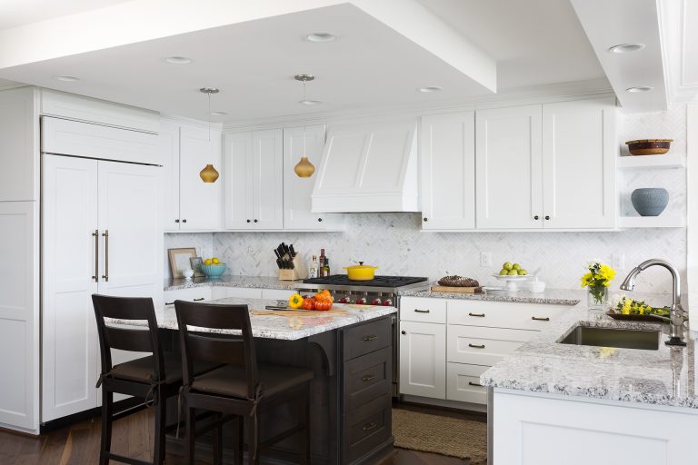 kitchen with white outer cabinets dark wood island with seating pendant lighting paneled refrigerator