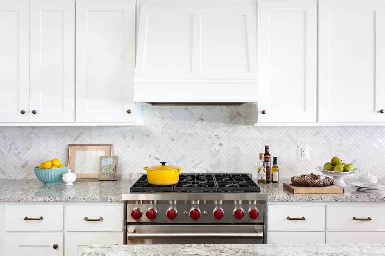 stainless steel gas stovetop and white paneled range hood