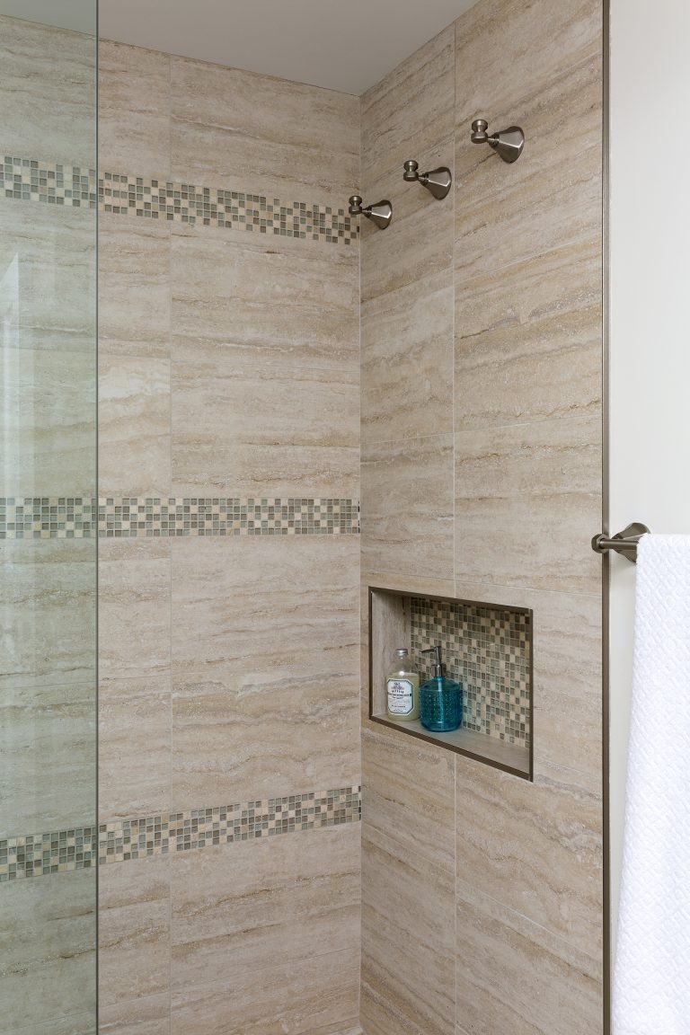 shower with nook built into wall with mosaic accent tile and stripe detail
