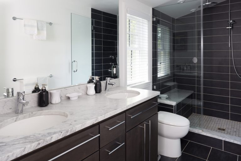 black and white bathroom shower with glass door and built in bench vanity with double sinks