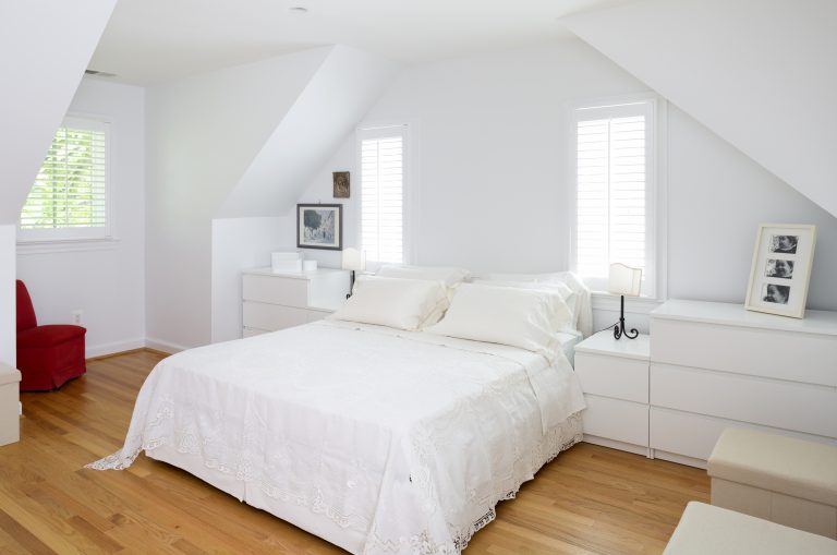 bright white attic bedroom with wood floors slanted roof and windows
