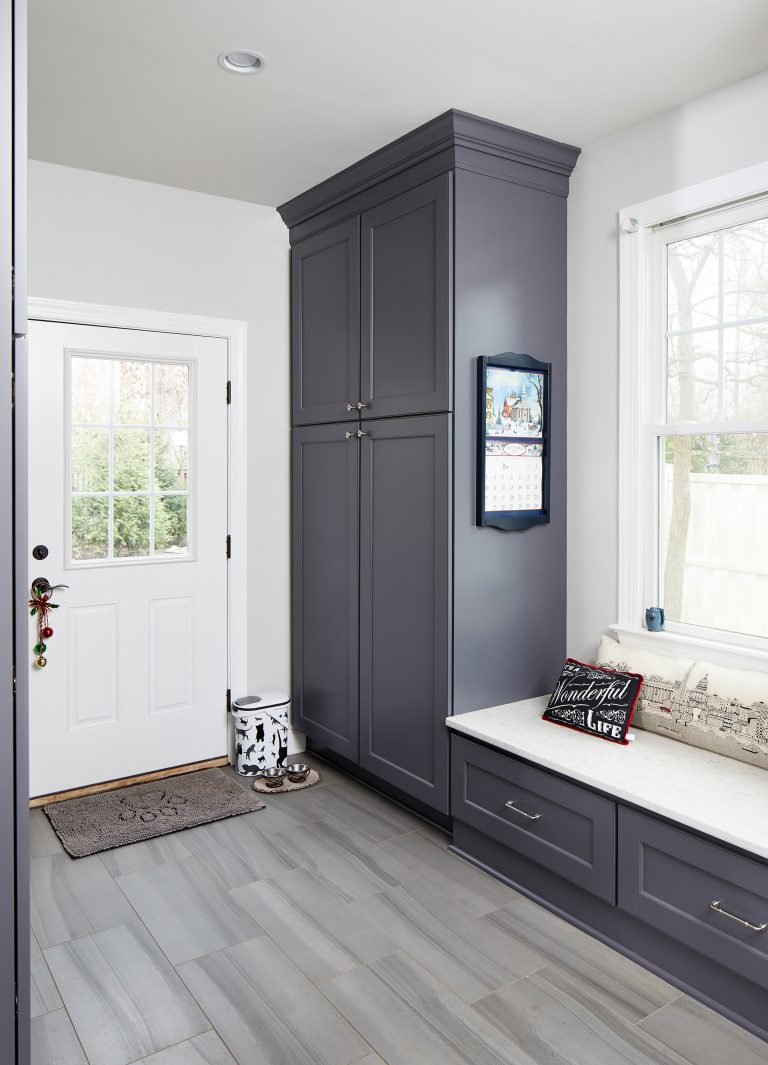 mudroom with grayish blue cabinetry plenty of storage and built in bench under window
