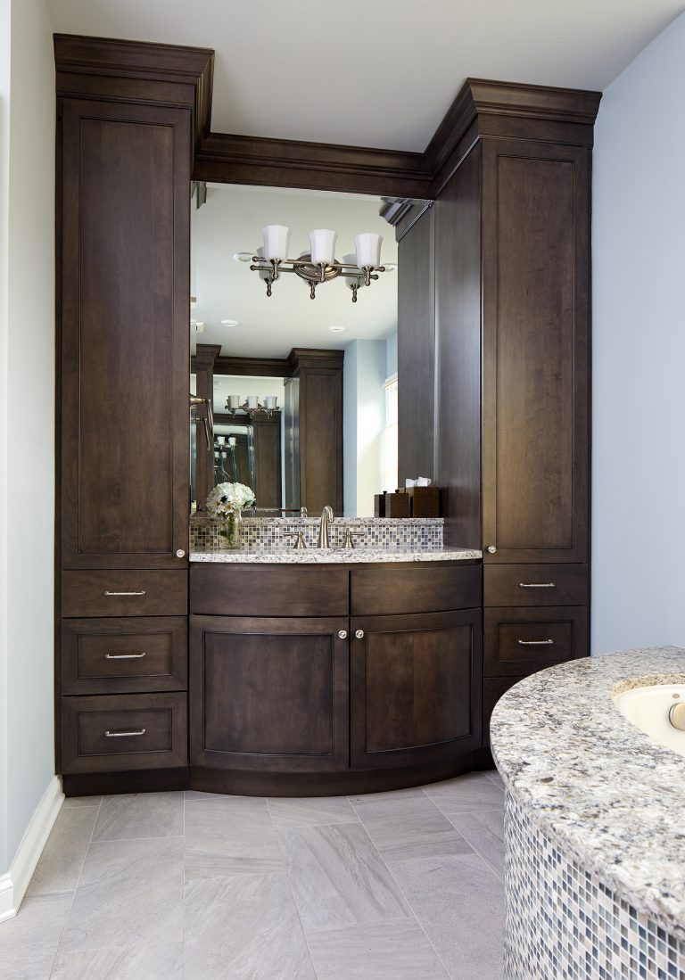 bathroom vanity curved front with plenty of storage dark stained cabinetry sconce lighting