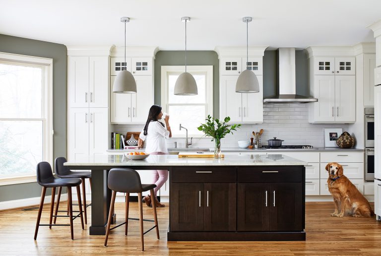 kitchen with wood floors white outer cabinets and dark stained island with seating pendant lighting