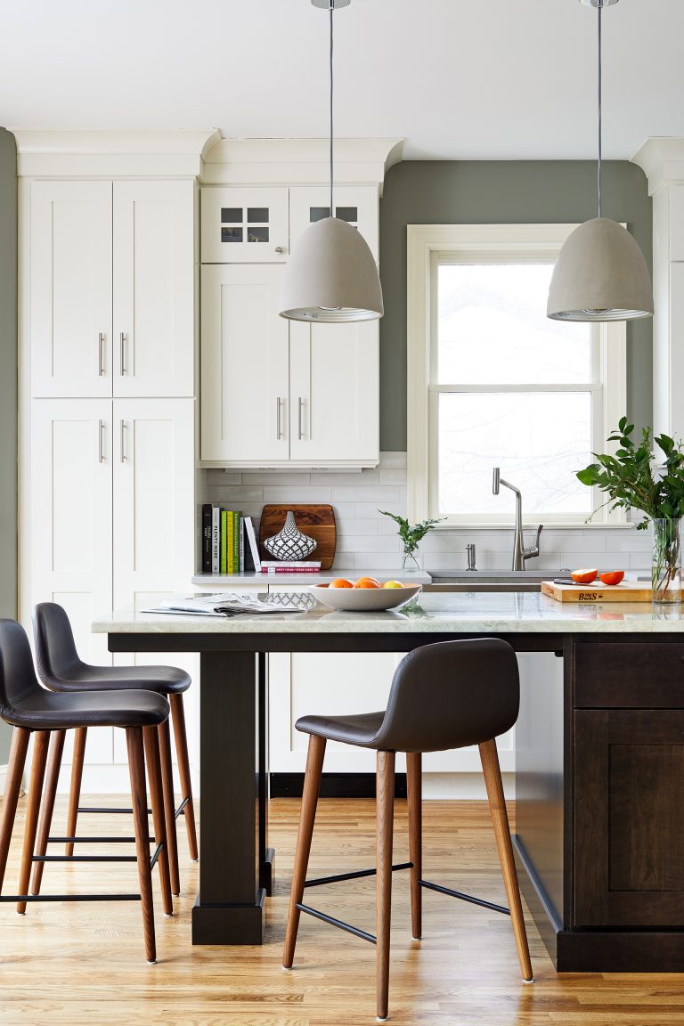 dark wood island with seating and pendant lighting white outer cabinetry floor to ceiling and glass uppers