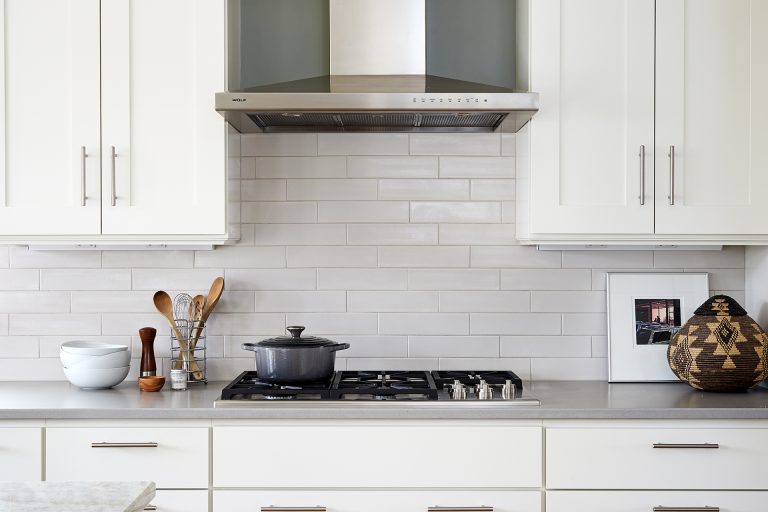 gas stovetop and stainless steel range hood white subway tile backsplash