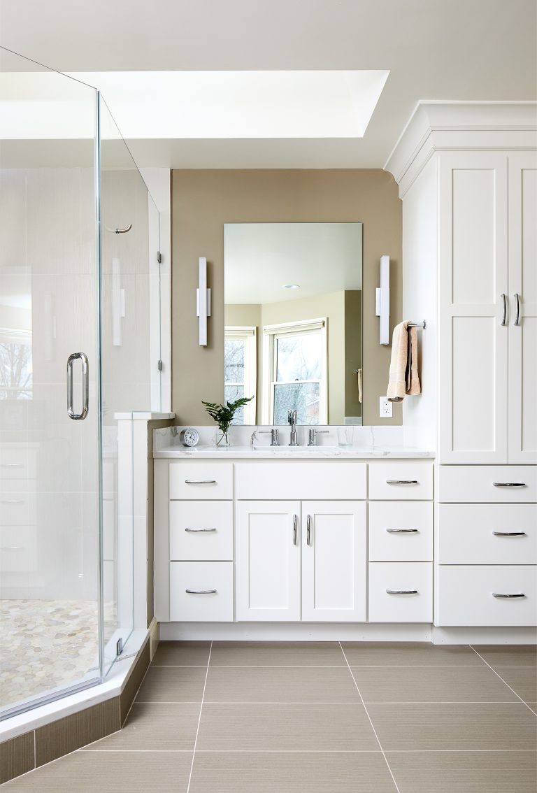 master bathroom shower and vanity with white floor to ceiling cabinetry sky light and sconce lighting