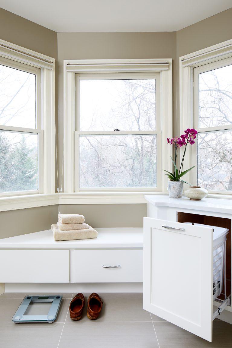 built in storage bench under windows and cabinetry to hide laundry hampers