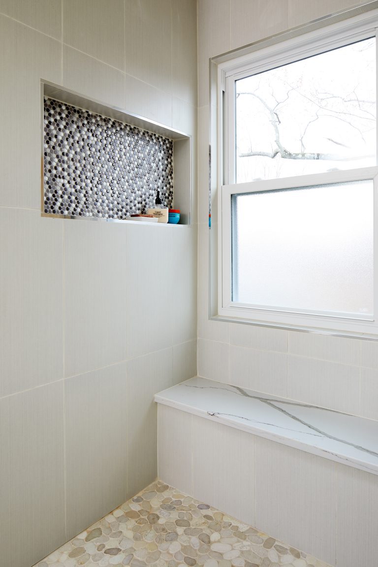 wall nook in shower with mosaic accent tile built in bench and frosted glass window