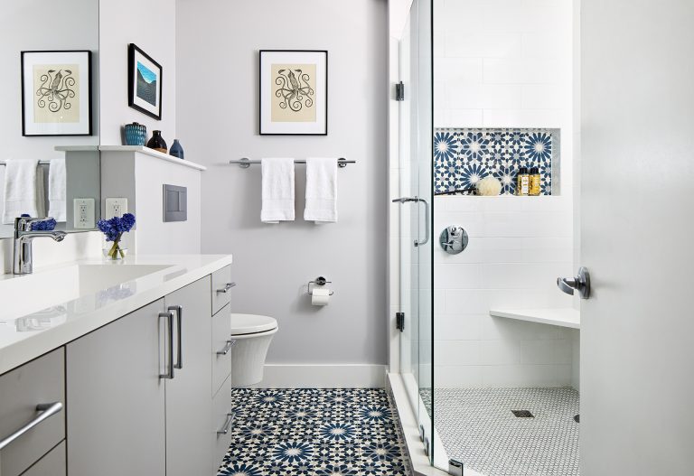 white bathroom shower with glass door and blue accent tile in nook built in bench