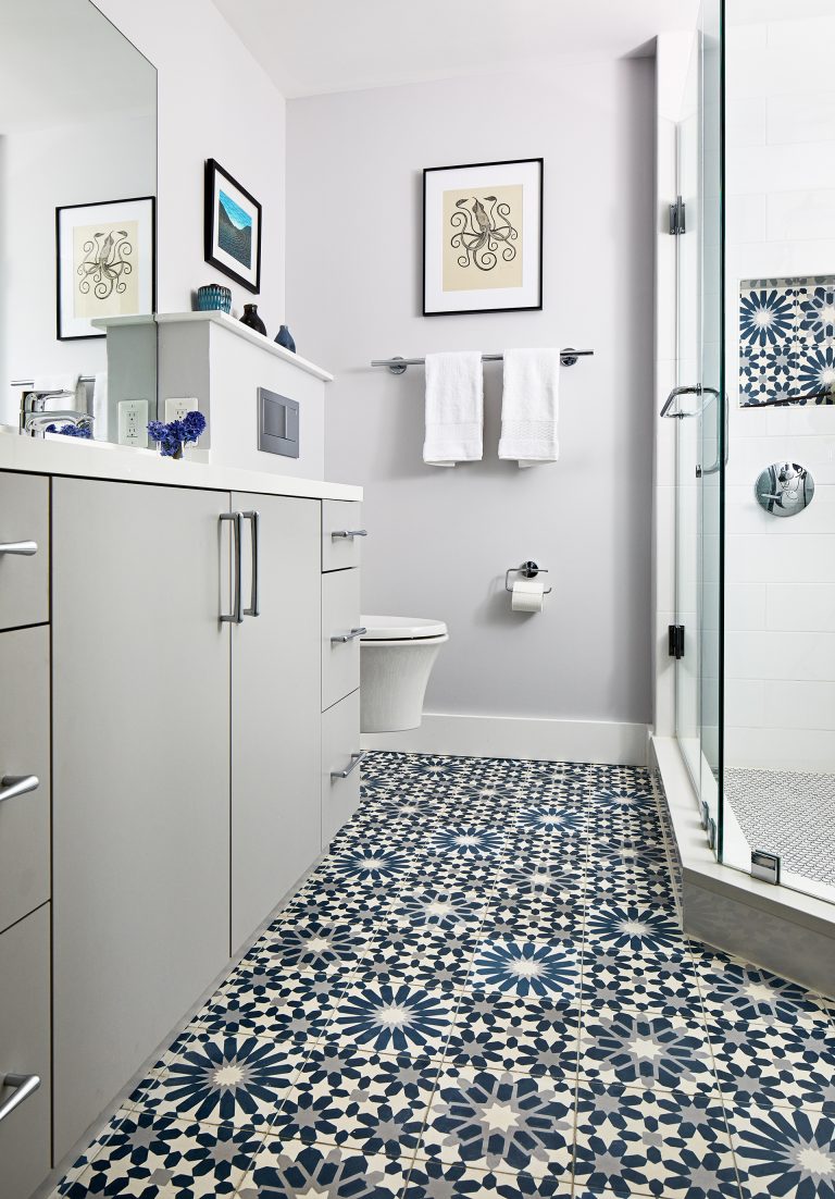 white bathroom with blue and black patterned tile on floors and storage nook