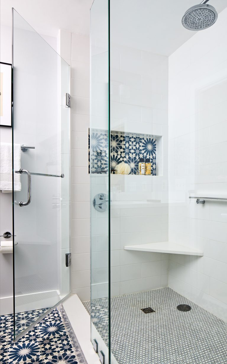 white bathroom shower with glass door and blue accent tile in nook built in bench